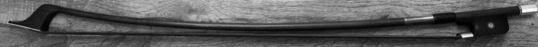 A double bass bow resting on a wooden floor